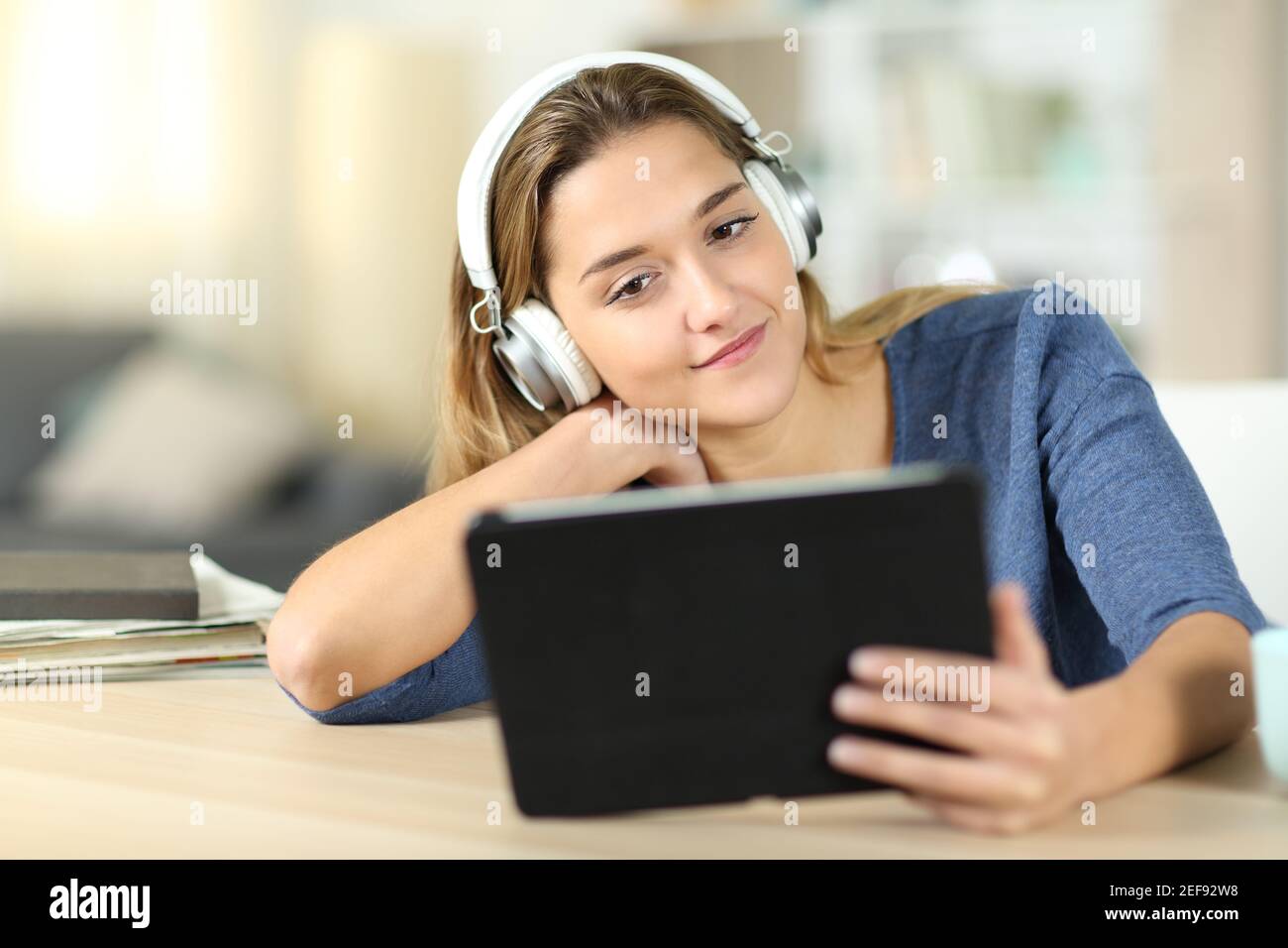 Femme satisfaite regardant des médias sur une tablette avec un casque à la maison Banque D'Images