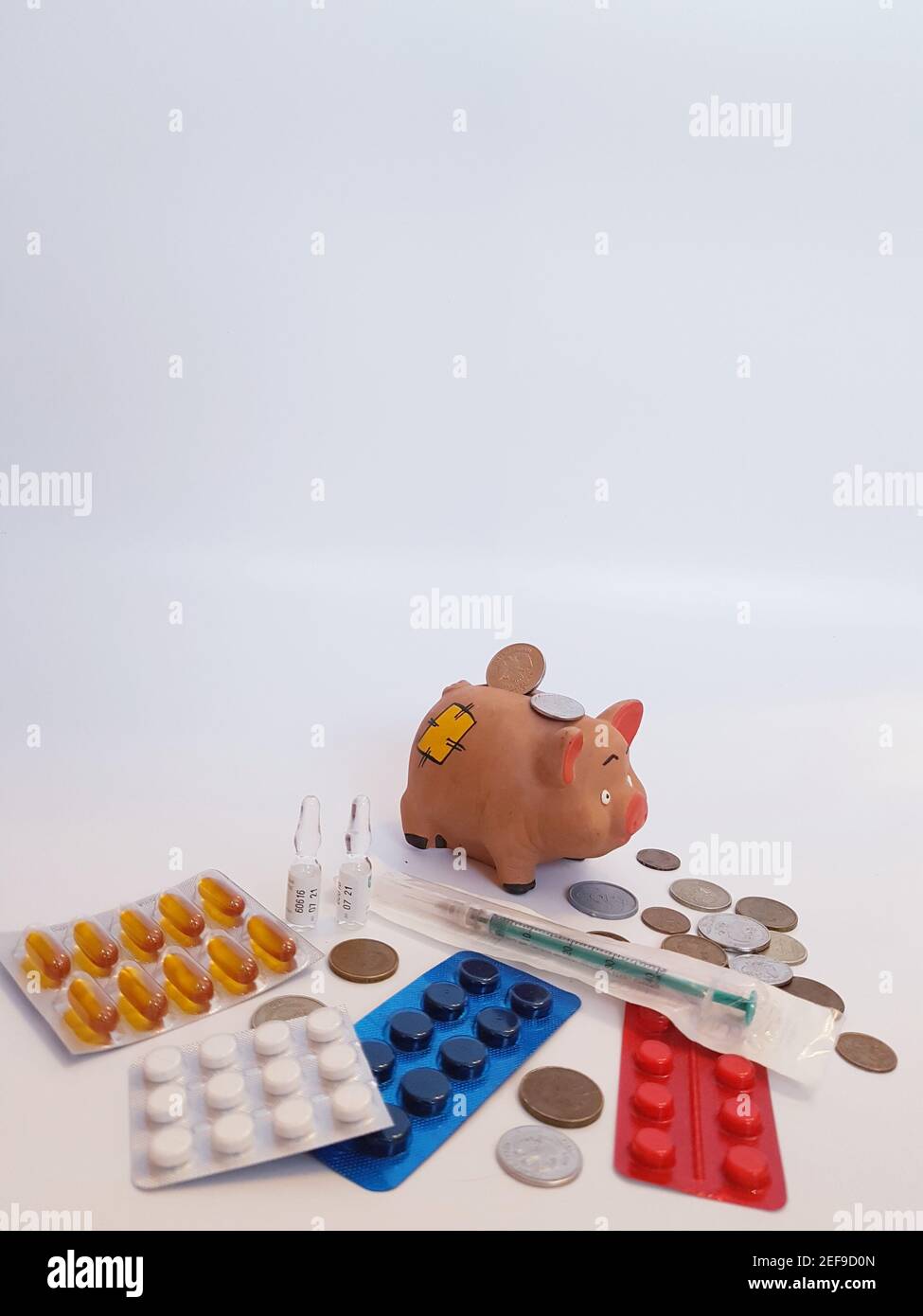Tirelire avec de l'argent, des pilules, des médicaments, une seringue, des ampoules sur fond blanc. Coûts de traitement. Gains sur les médicaments. Banque D'Images