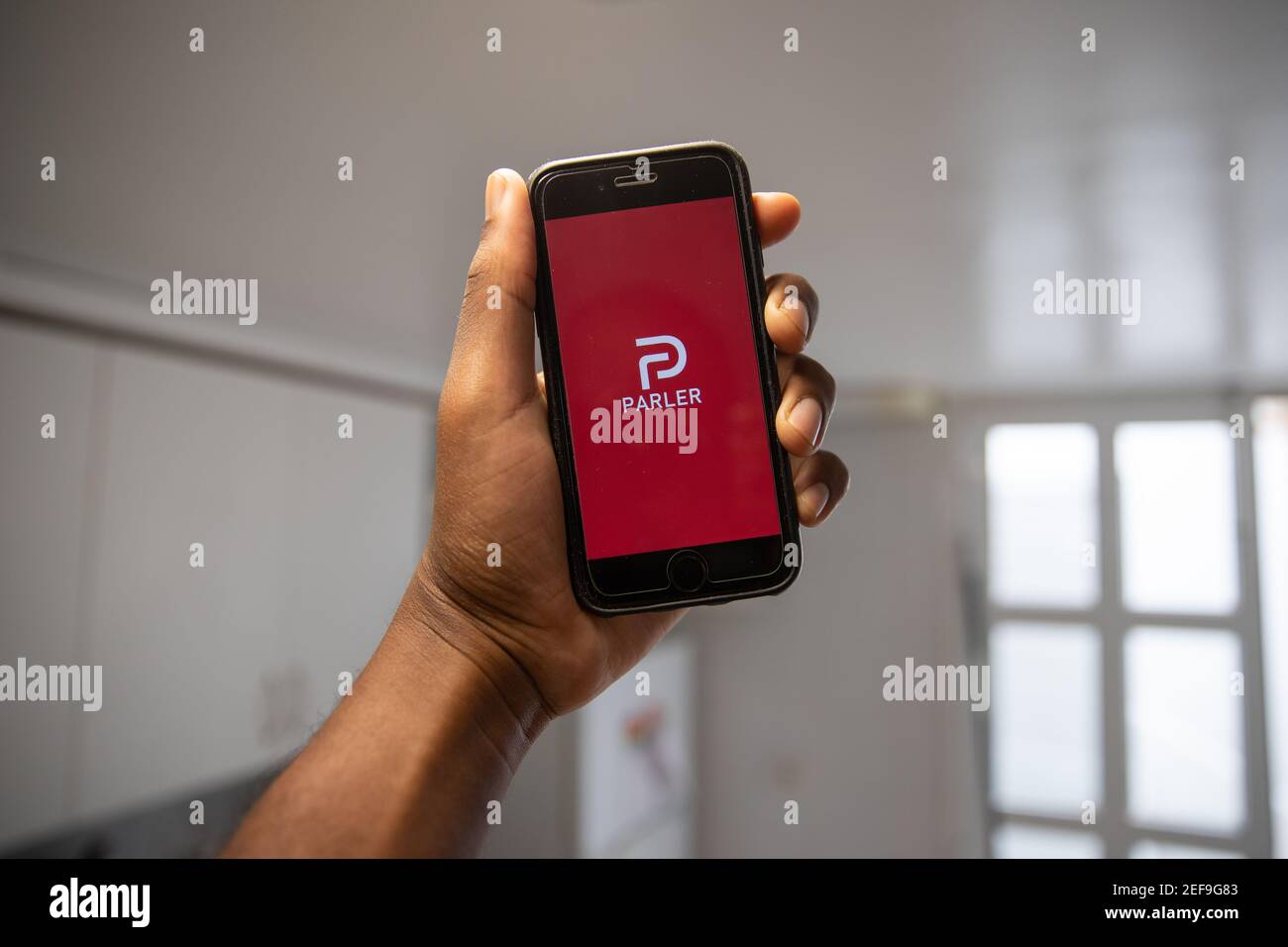 Un homme tient un smartphone avec le logo Parler dans sa main. Parler est un réseau social devenu très populaire lors des élections américaines Banque D'Images