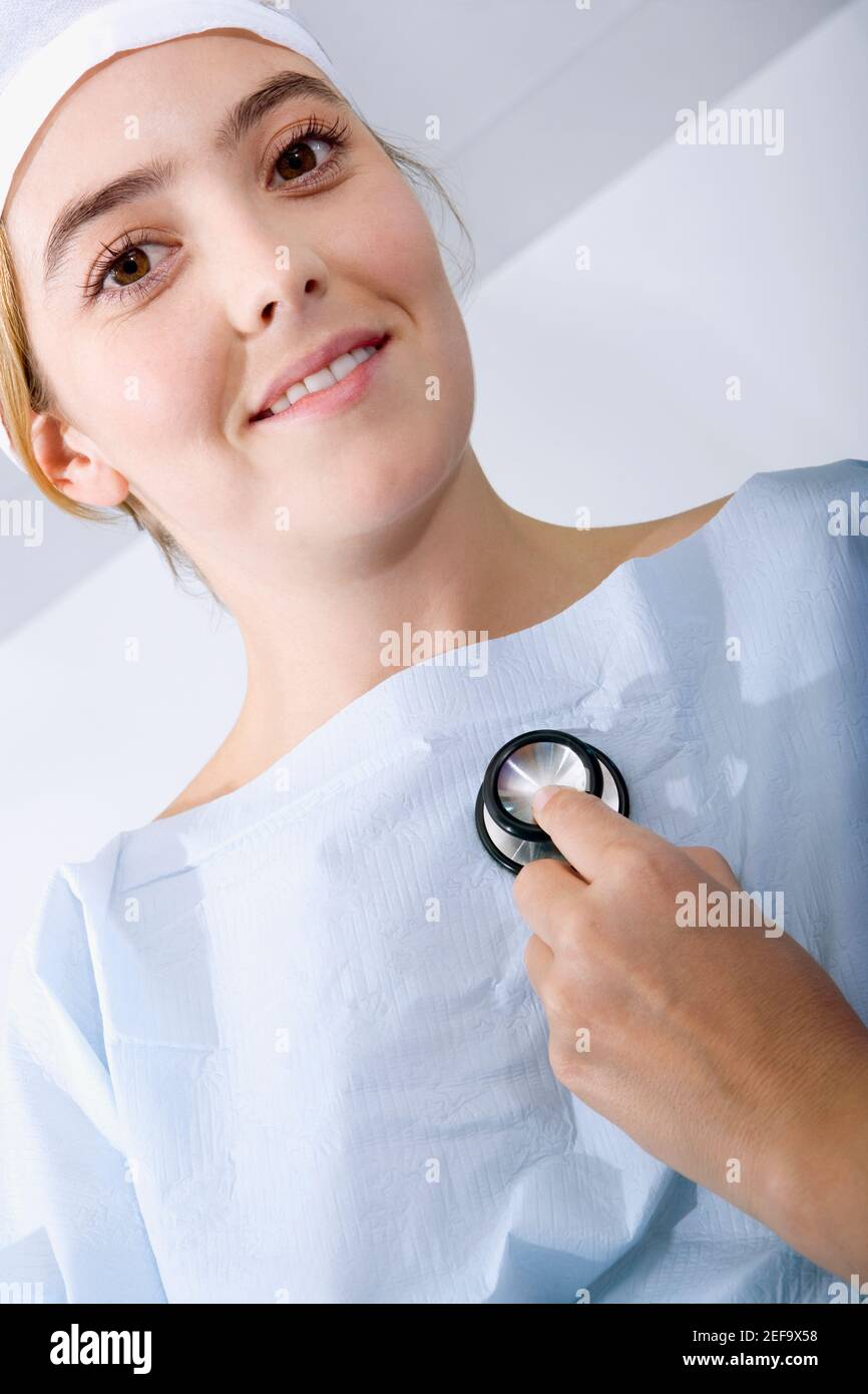 Gros plan d'une main de doctorÅthoscope tenant un stéthoscope et examinant une patiente Banque D'Images