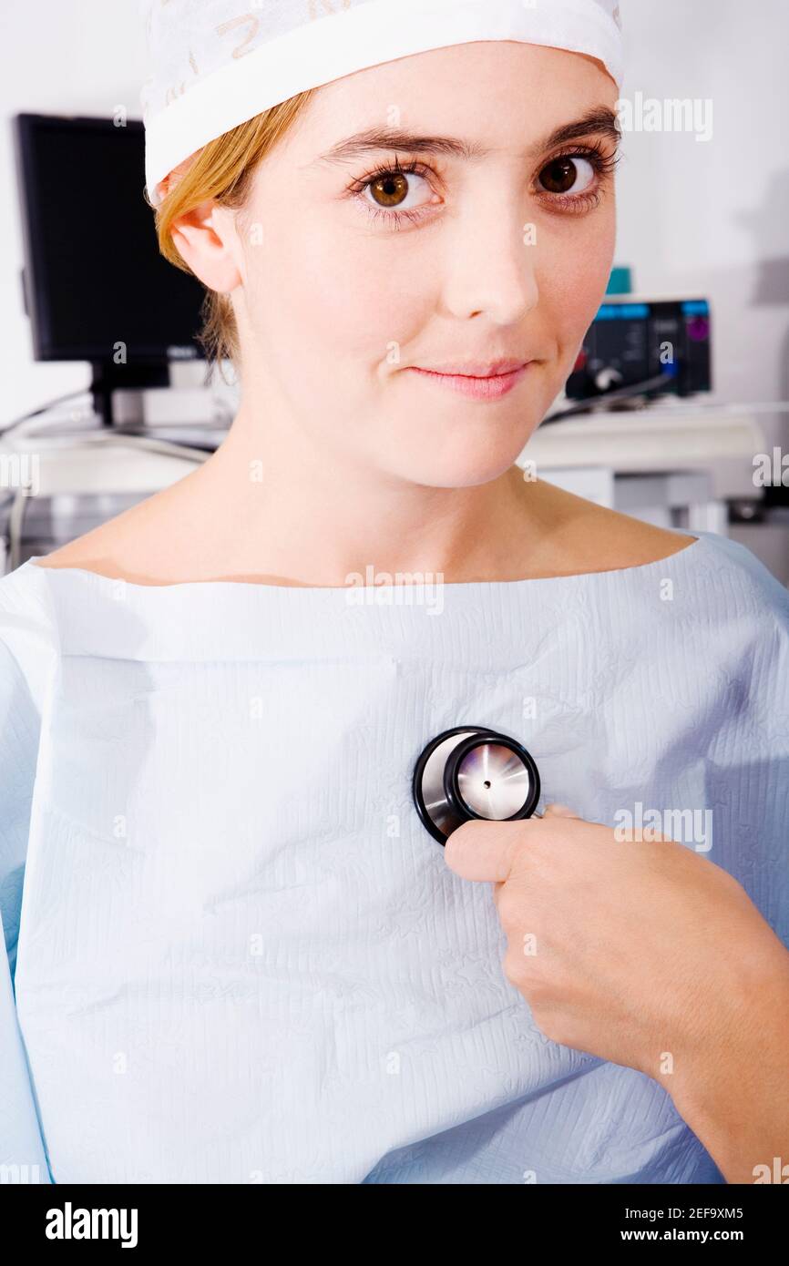 Gros plan d'une main de doctorÅthoscope tenant un stéthoscope et examinant une patiente Banque D'Images