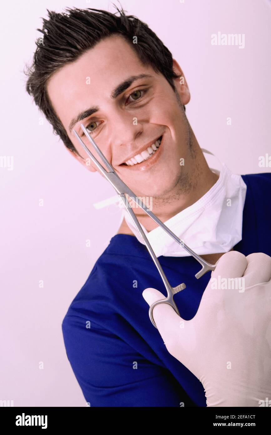 Portrait d'un chirurgien mâle tenant une ciseaux chirurgicaux et sourire Banque D'Images