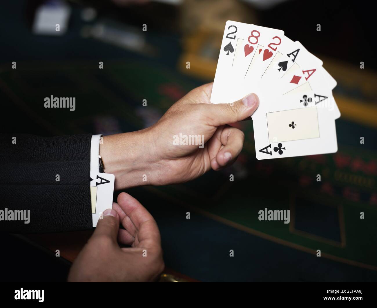 Gros plan d'une main de personnage tenant des cartes à jouer et se cachant un as dans son poignet Banque D'Images