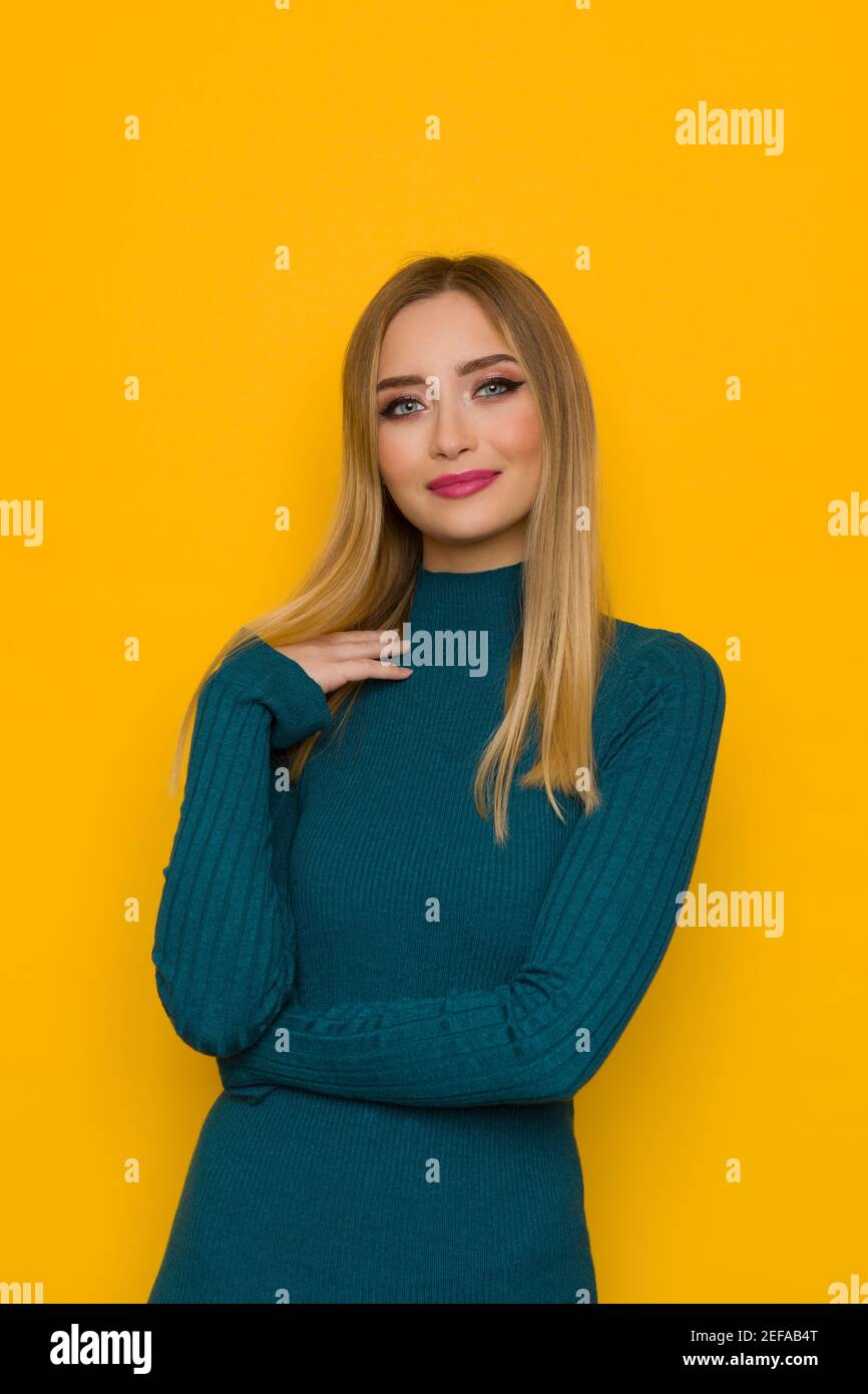 Portrait de belle jeune femme gaie en robe ajustée sarcelle. Taille haute studio tourné sur fond jaune. Banque D'Images