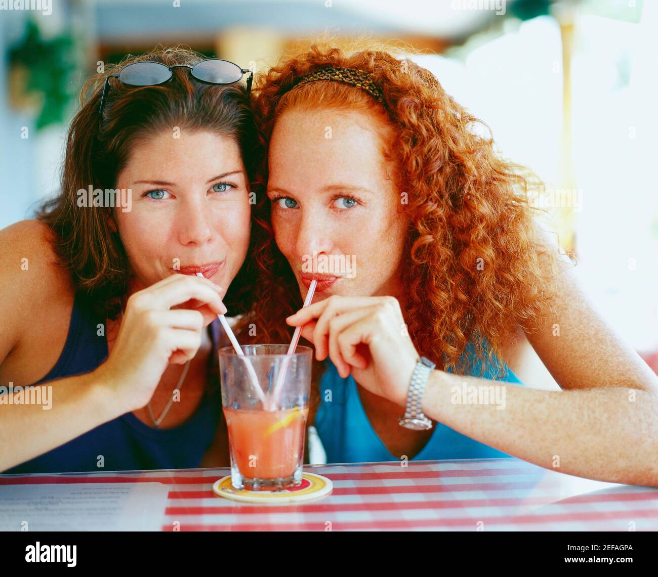 Portrait de deux jeunes femmes buvant du jus d'un verre avec pailles, Bermudes Banque D'Images