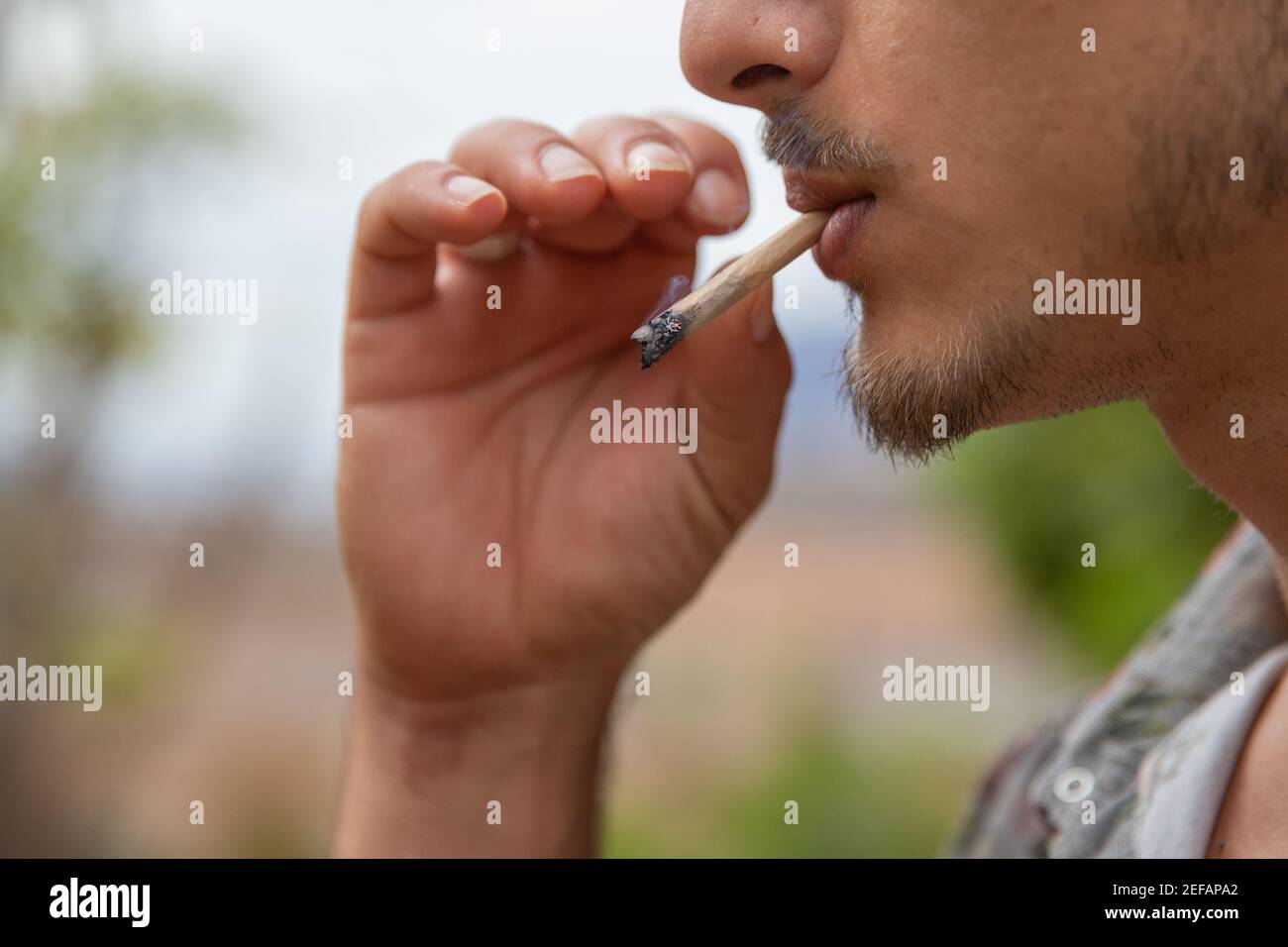 Gros plan Portrait d'un homme qui fume un joint de la marijuana Banque D'Images