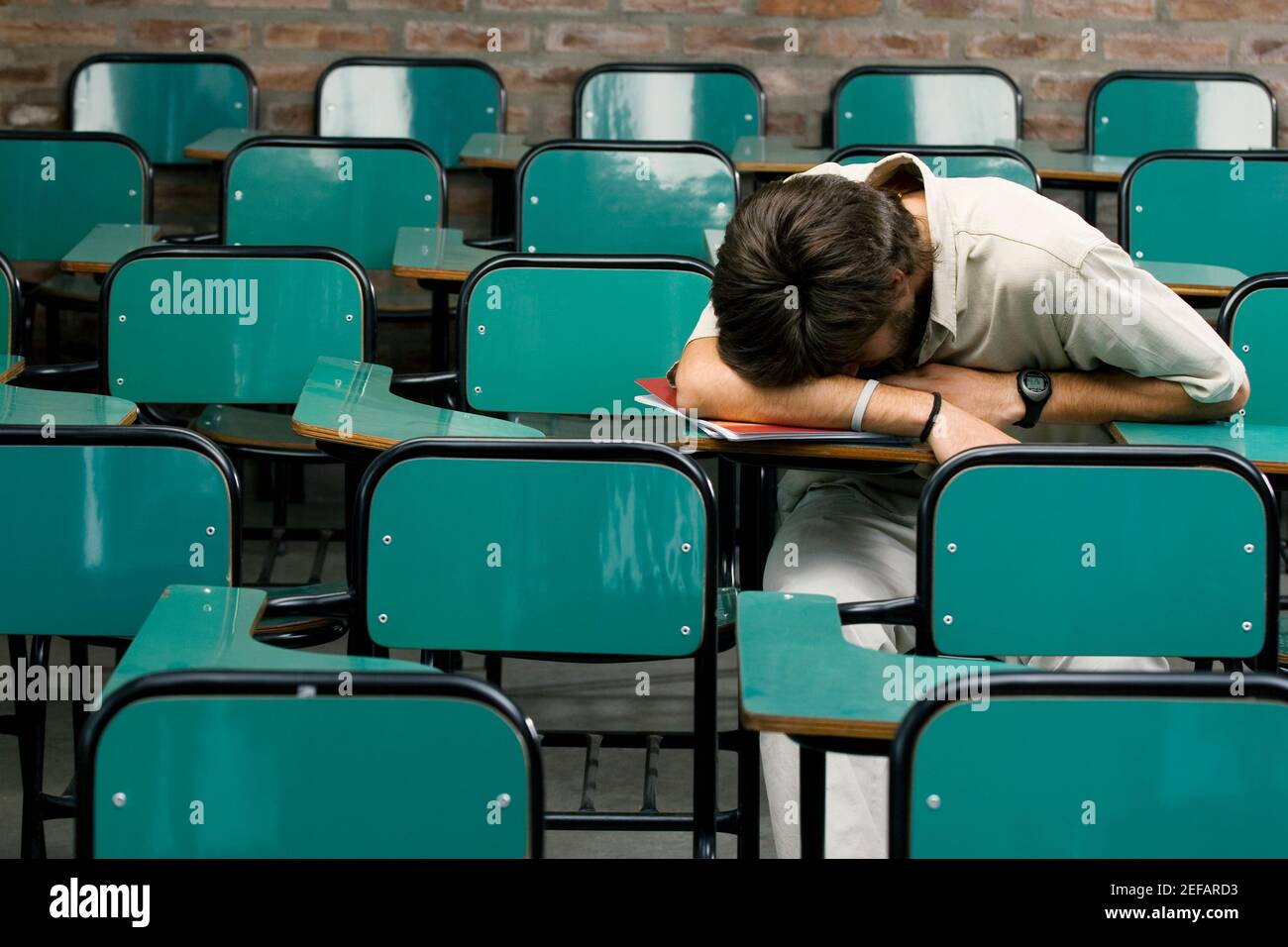 Un jeune homme qui fait la sieste dans une salle de classe Banque D'Images