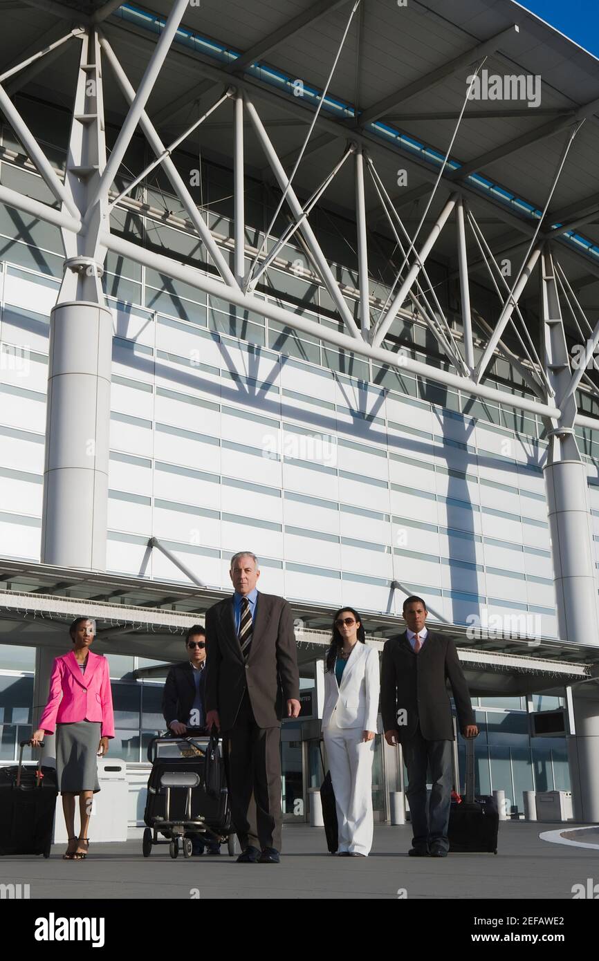 Trois hommes d'affaires avec deux femmes d'affaires à l'extérieur dans un aéroport Banque D'Images