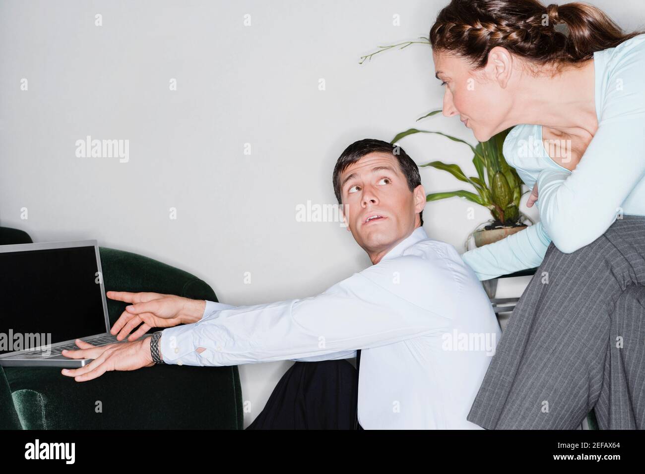 Homme d'affaires travaillant sur un ordinateur portable et regardant une femme d'affaires Banque D'Images