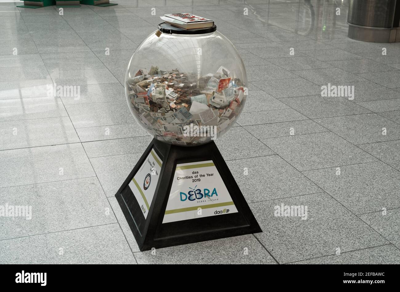 DUBLIN, IRLANDE - 15 janvier 2020 : vue sur un contenant en verre en forme de balle avec de l'argent collecté pour la charité 'DEBRA Ireland' dans le hall vide de Dublin Air Banque D'Images