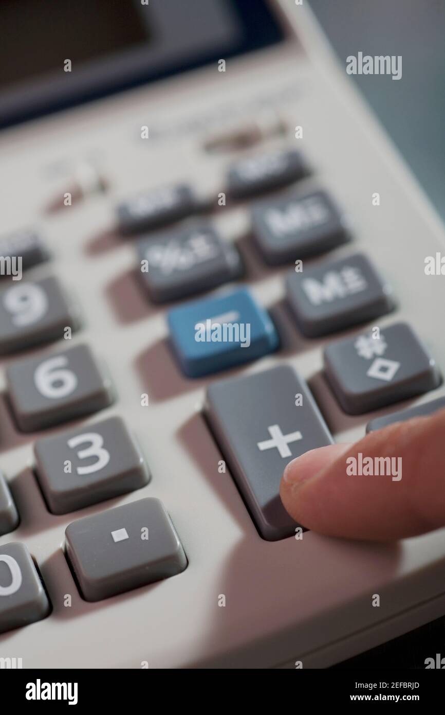 Gros plan d'un doigt humain appuyant sur les boutons d'une calculatrice Banque D'Images