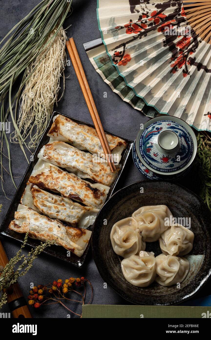 Matériel de boulettes traditionnelles chinoises frites (également appelé gyoza, étiquette de pot) sur table avec fond noir et décorer de style chinois ventilateurs et Banque D'Images