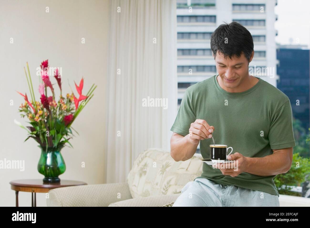 Homme adulte moyen remuant le thé avec une cuillère à café Banque D'Images