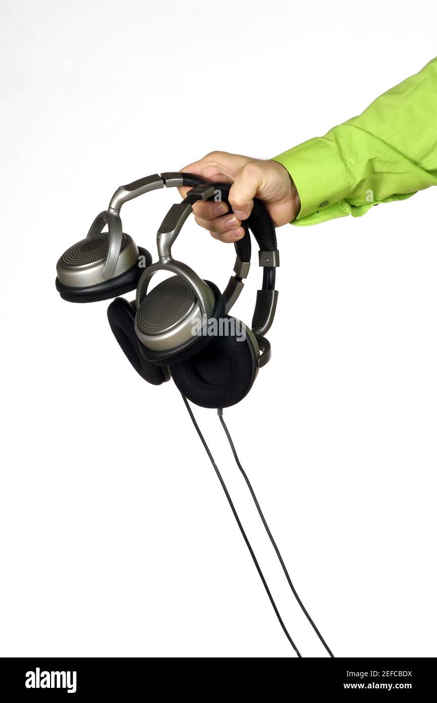 Gros plan d'une main de homme tenant deux paires de casques Banque D'Images