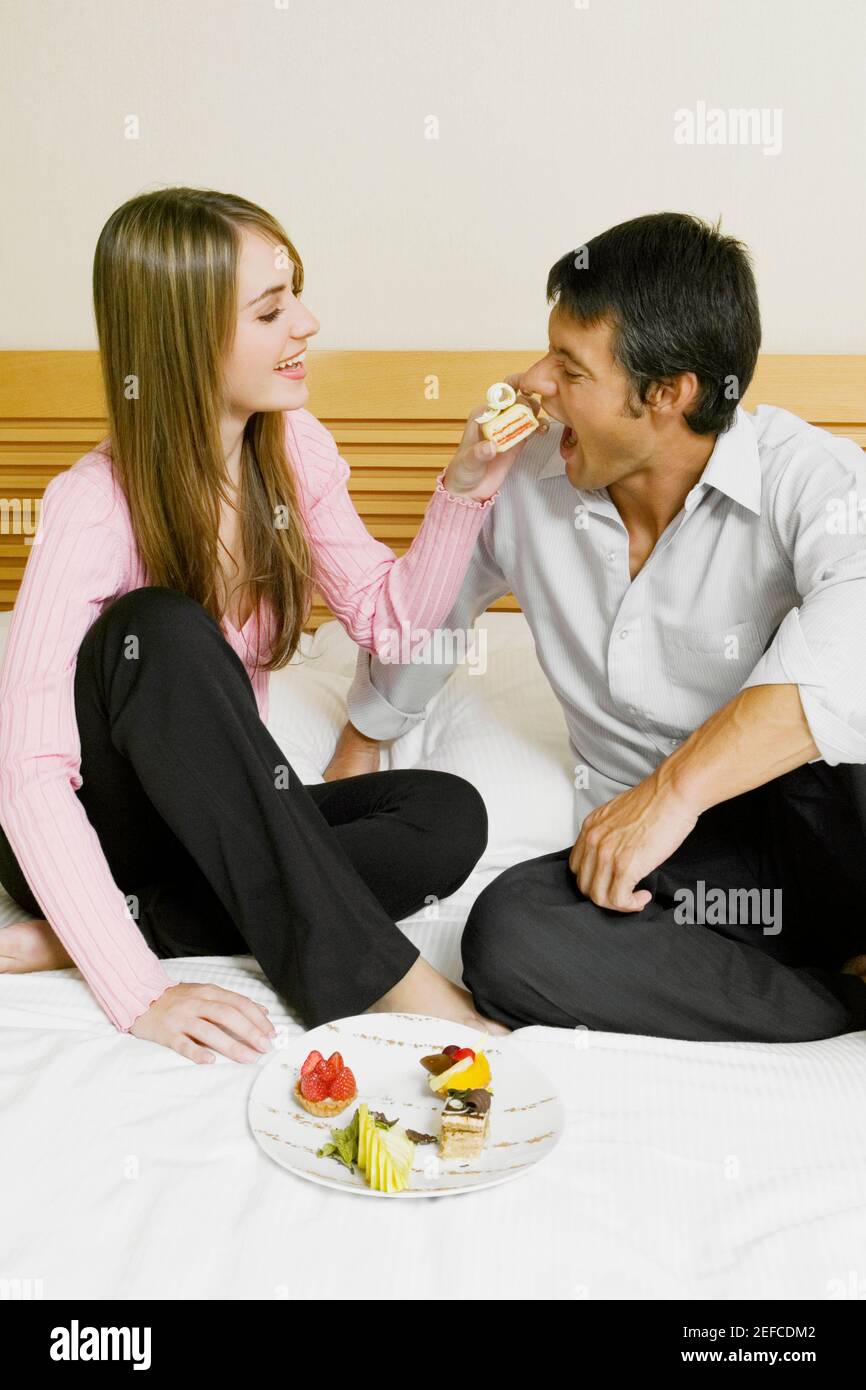 Jeune femme nourrissant un gâteau à un homme adulte moyen Banque D'Images