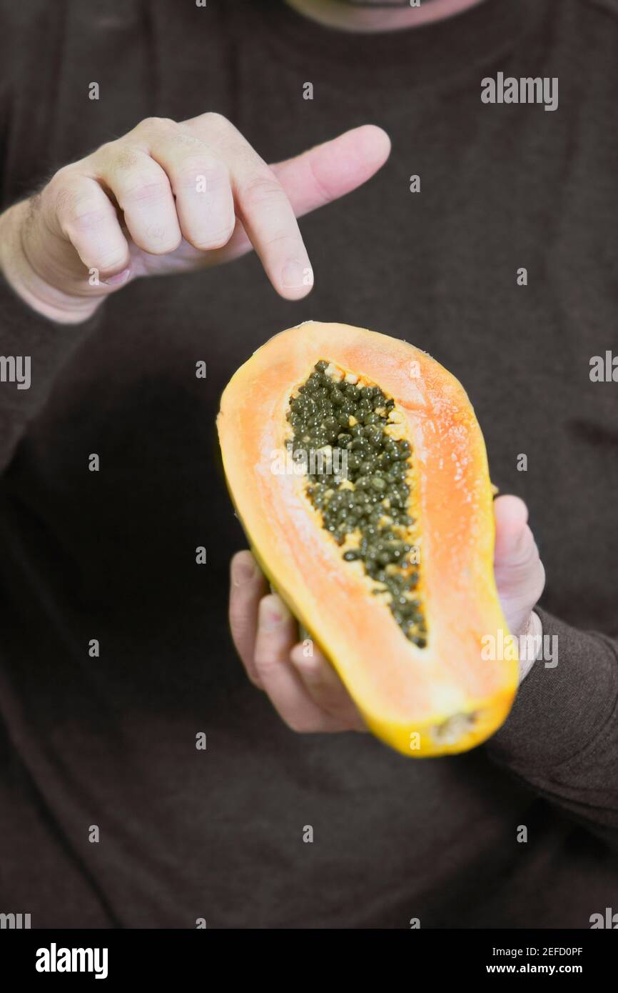 Vue en coupe centrale d'un homme tenant la moitié de une papaye Banque D'Images