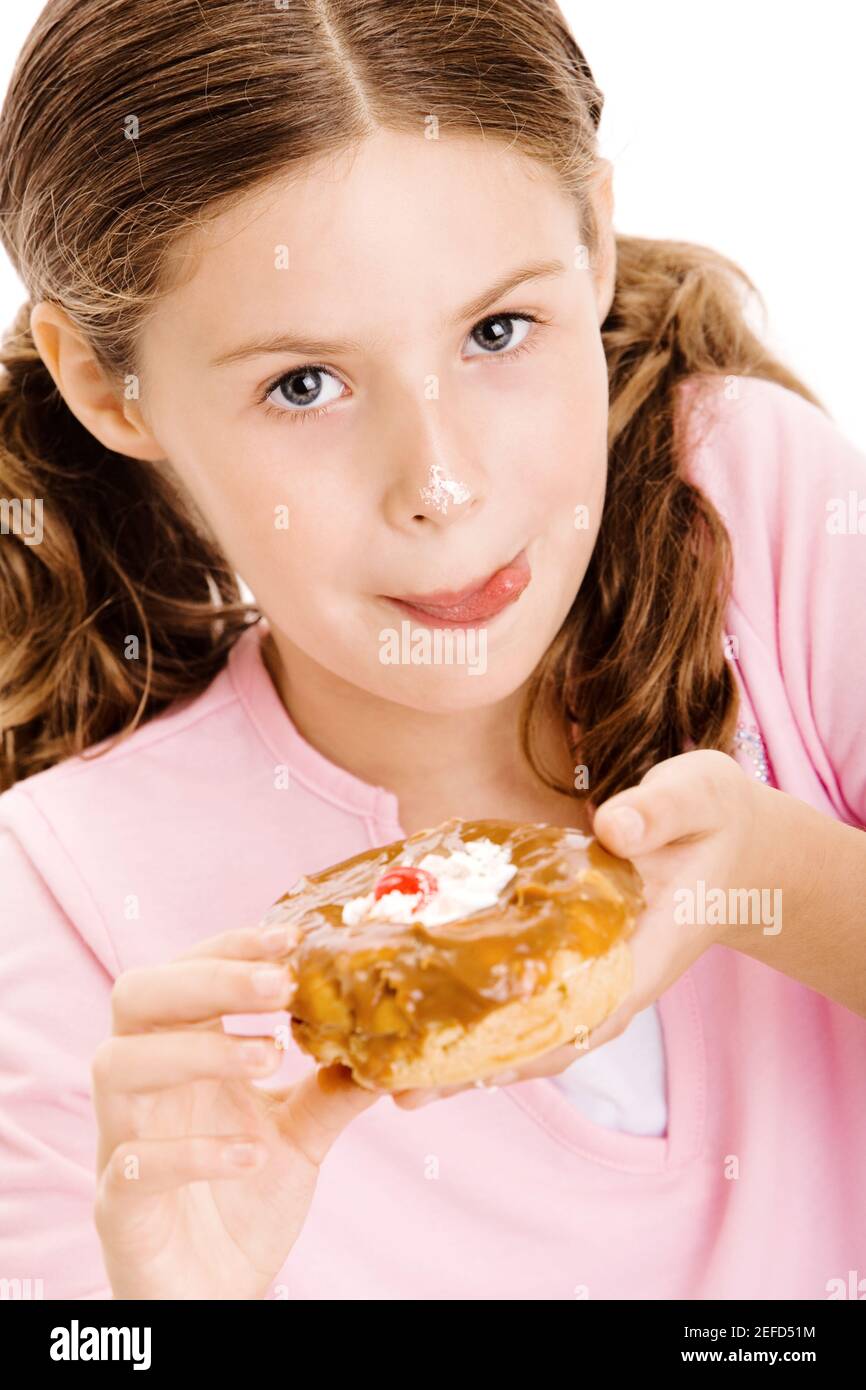 Portrait d'une fille tenant un donut léchant ses lèvres Banque D'Images