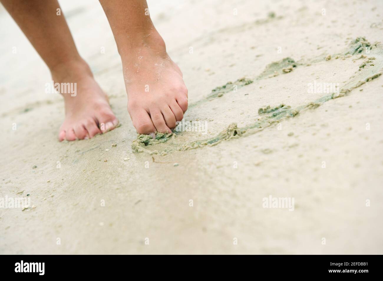 Vue en coupe basse d'une femme dessinant dans le sable avec son orteil  Photo Stock - Alamy
