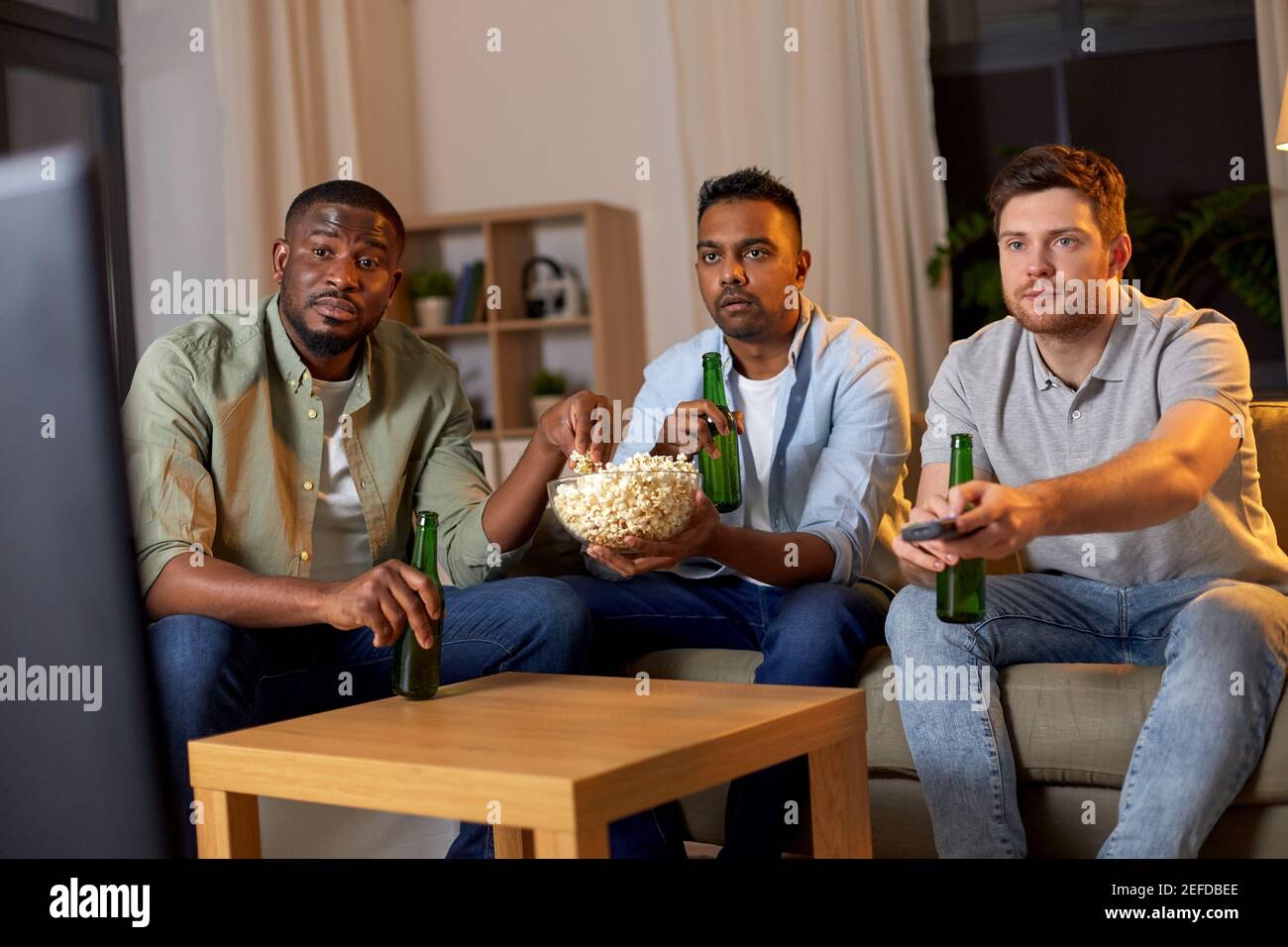 amis masculins avec bière regardant la télévision à la maison Banque D'Images
