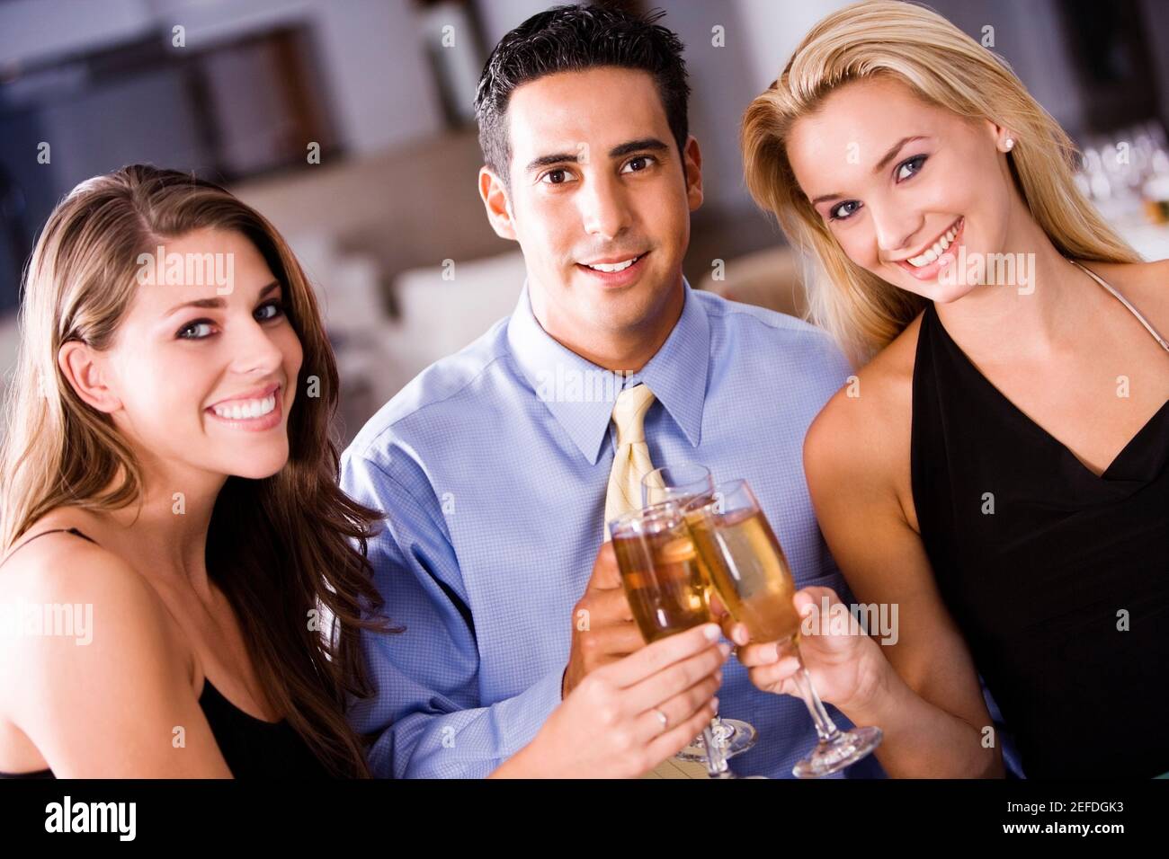 Portrait d'un homme adulte moyen et de deux jeunes femmes porter un toast Banque D'Images