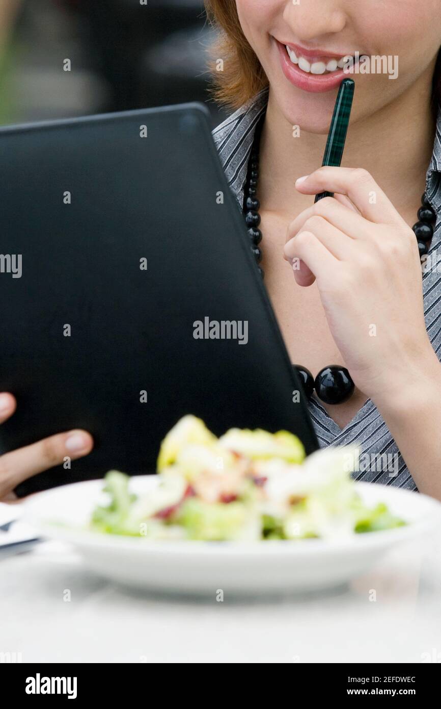 Femme d'affaires tenant une reliure à anneaux dans un café-terrasse Banque D'Images