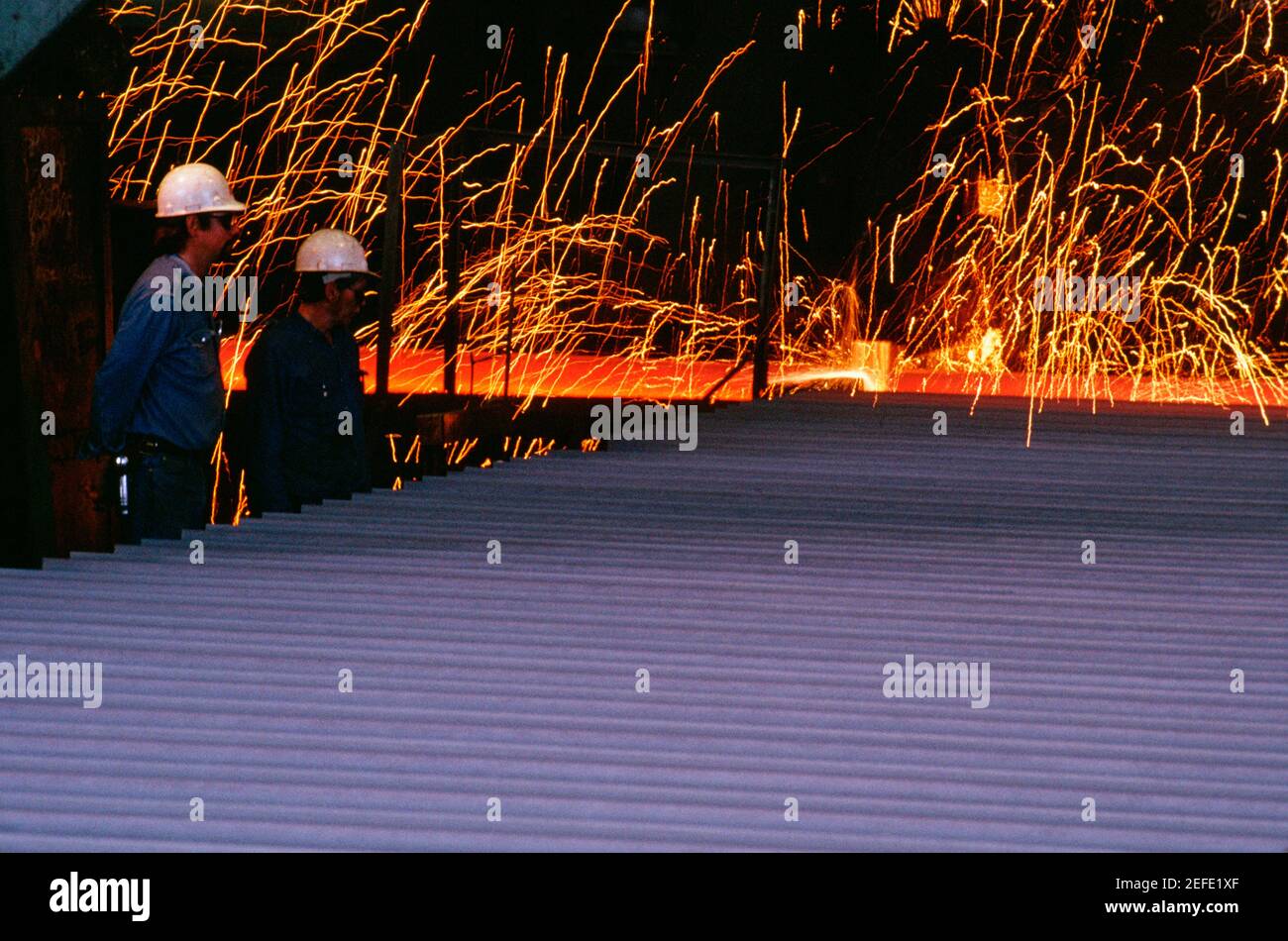 Profil latéral de deux ouvriers de fonderie debout dans un acier broyeur Banque D'Images