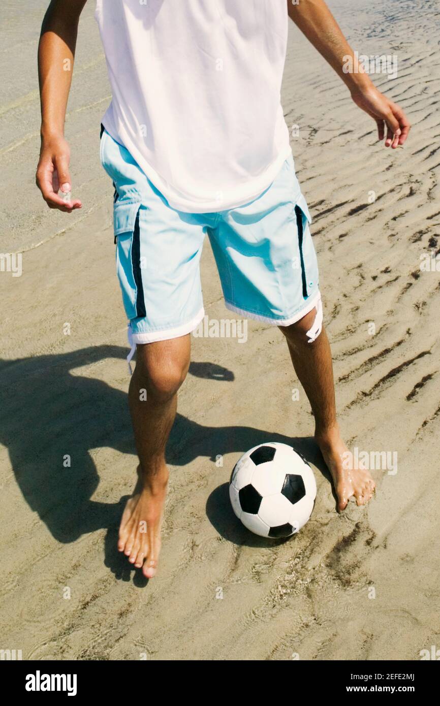 Vue en coupe basse d'une personne jouant avec un football ballon sur la plage Banque D'Images