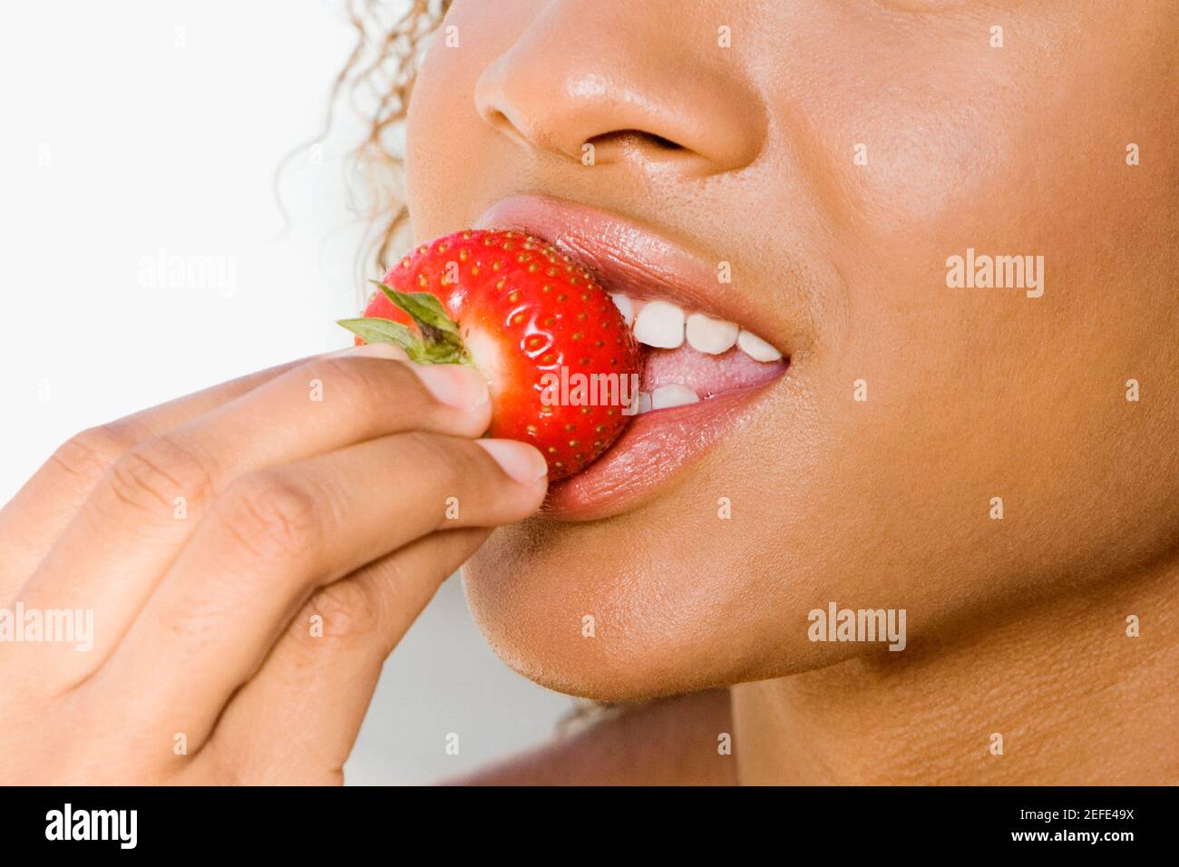 Close-up of a young woman eating a strawberry Banque D'Images