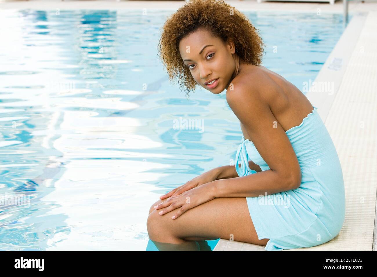 Portrait d'une jeune femme assise au bord de une piscine Banque D'Images