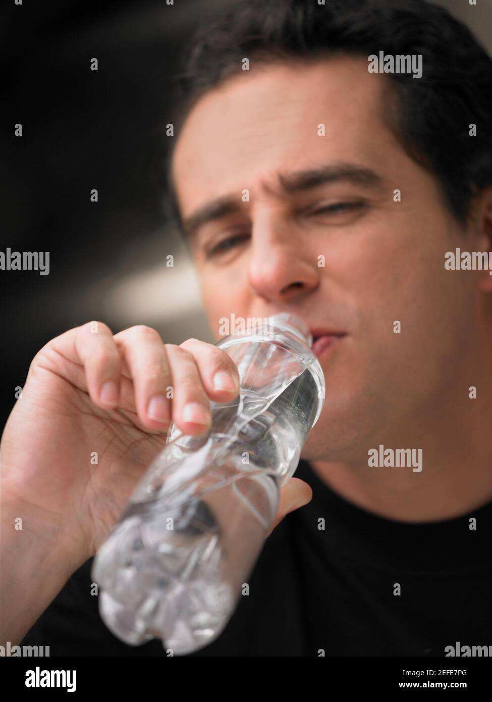 Gros plan d'un homme mature qui boit de l'eau dans une bouteille Banque D'Images
