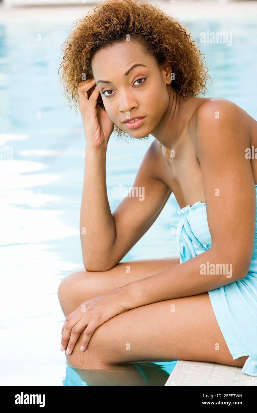 Portrait d'une jeune femme assise au bord de une piscine avec sa main sur son temple Banque D'Images