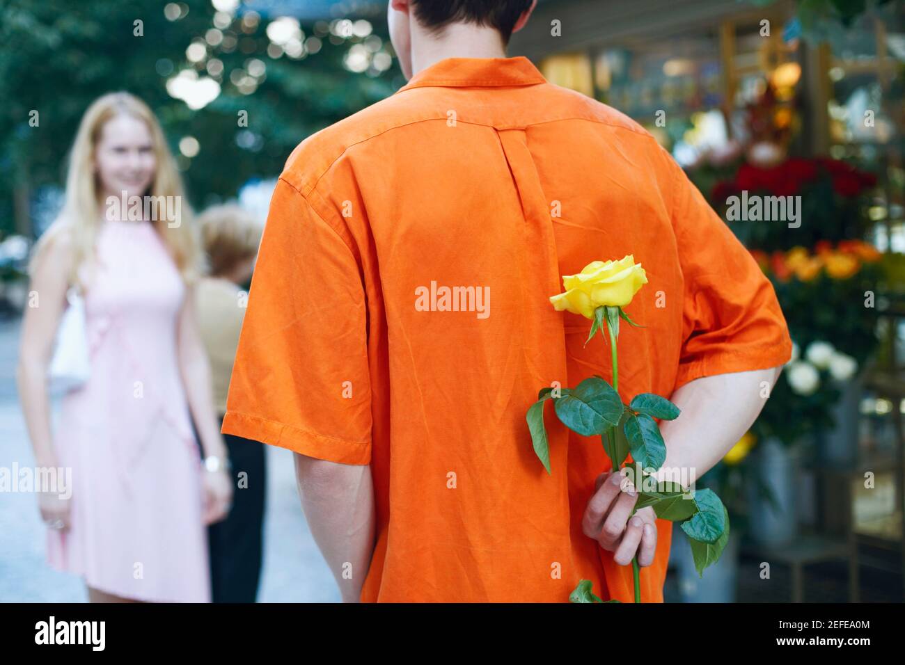 L'homme se cachant derrière son dos une fleur Banque D'Images