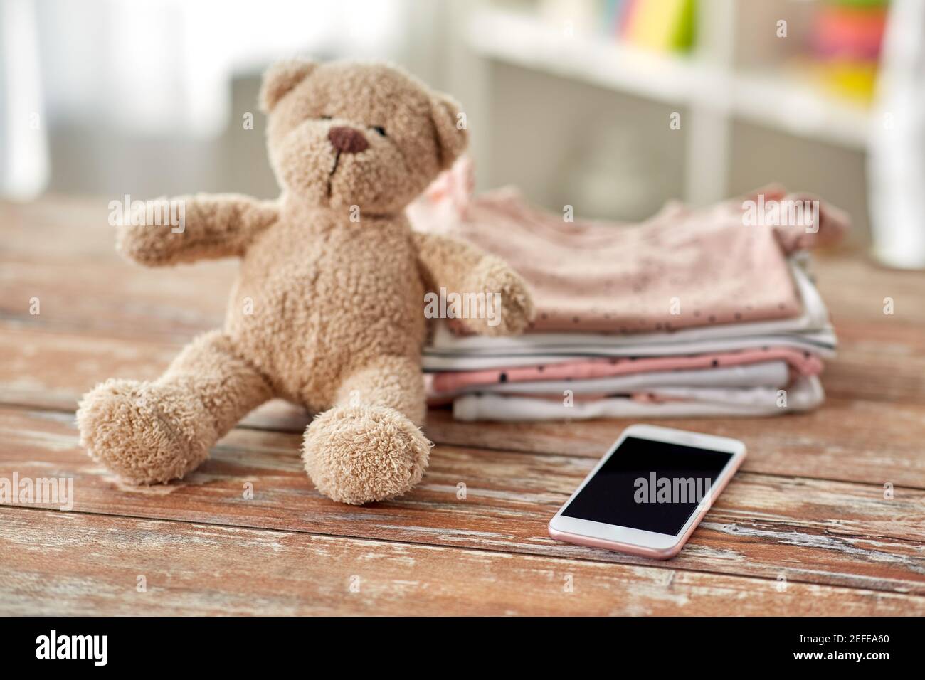 vêtements pour bébés, jouet ours en peluche et smartphone Banque D'Images