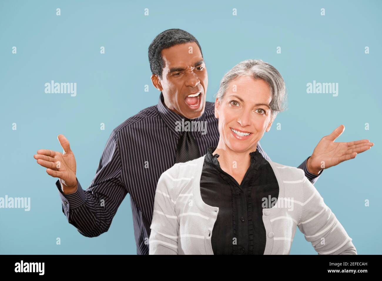 Portrait d'une femme d'affaires souriant avec un homme d'affaires criant à elle Banque D'Images