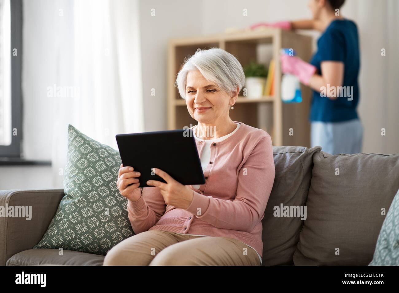 vieille femme avec tablette pc et femme de ménage à la maison Banque D'Images