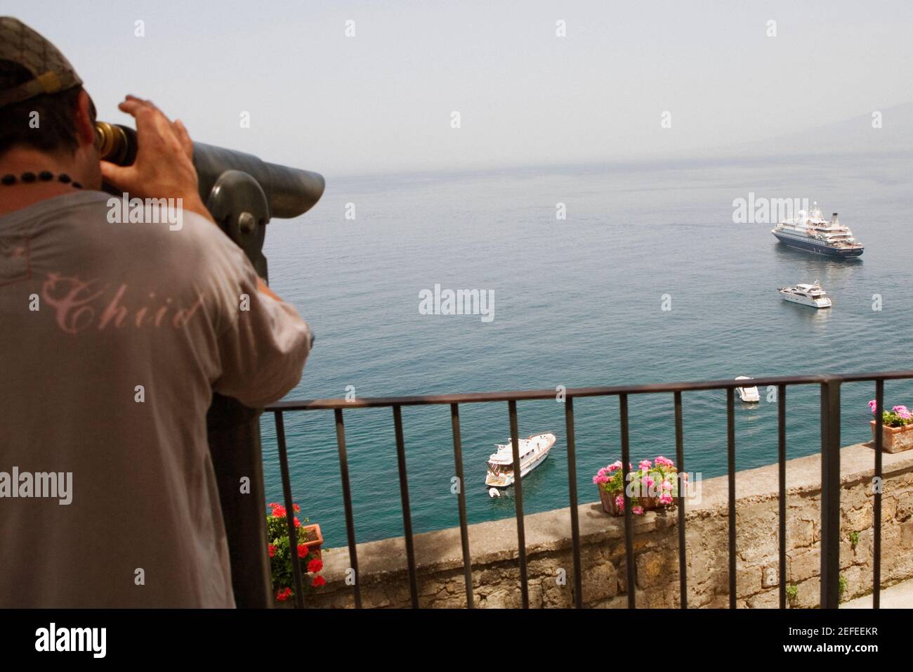 Vue arrière d'un homme regardant à travers un binoculaire à pièces, baie de Naples, via Aniello Califano, Sorrento, péninsule de Sorrentine, Province de Naples, Campanie, Italie Banque D'Images