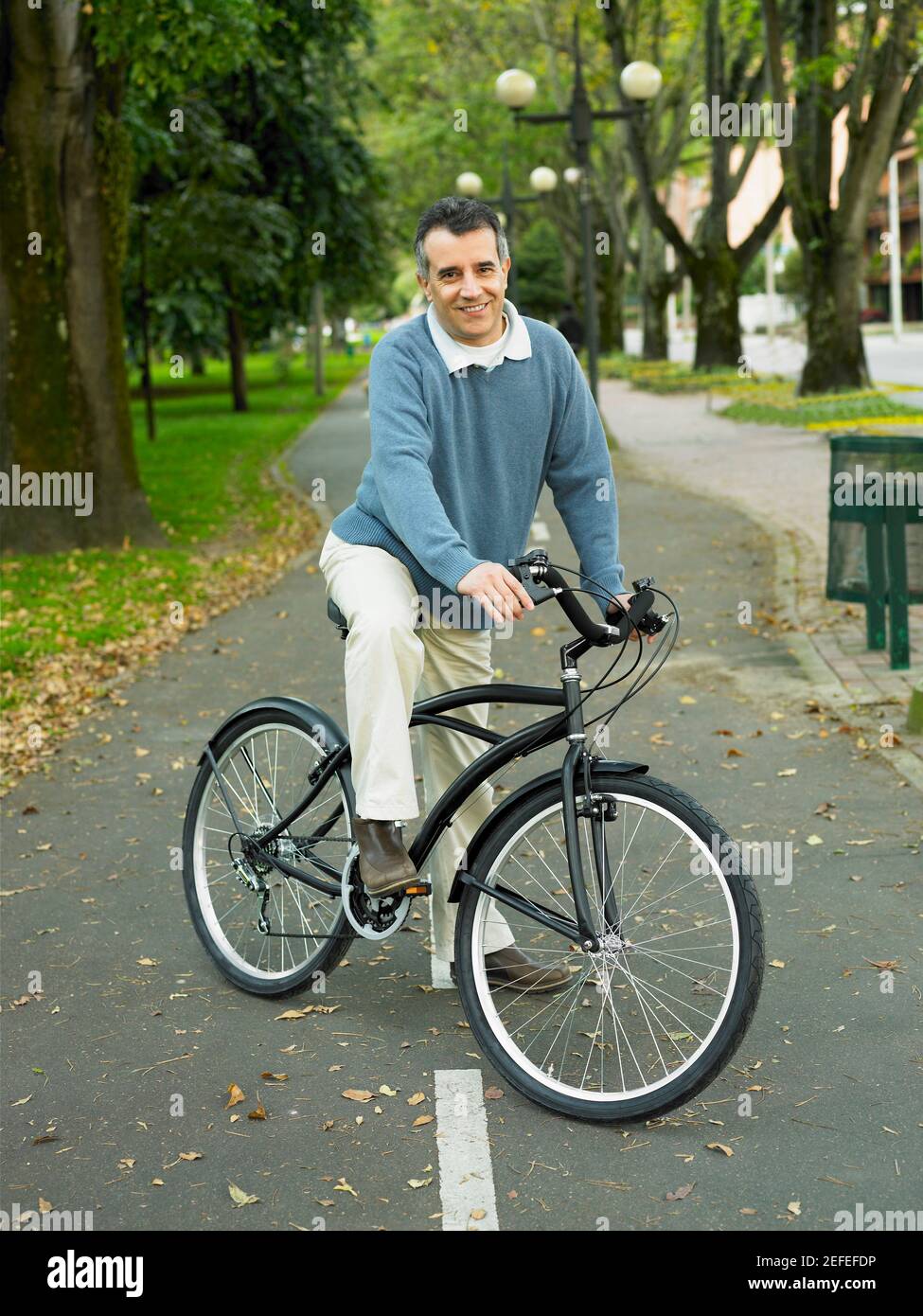 Portrait d'un homme mûr à vélo dans le stationnement Banque D'Images