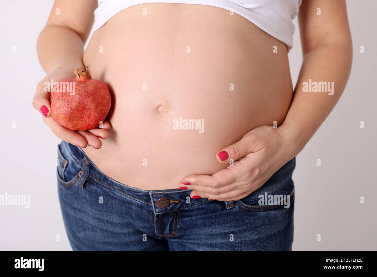 Femme porte des fruits grenat à son ventre enceinte Banque D'Images