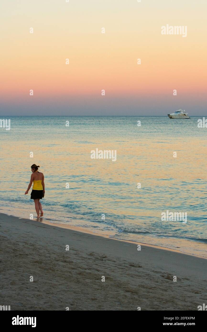 Vue arrière d'une femme marchant sur la plage Banque D'Images