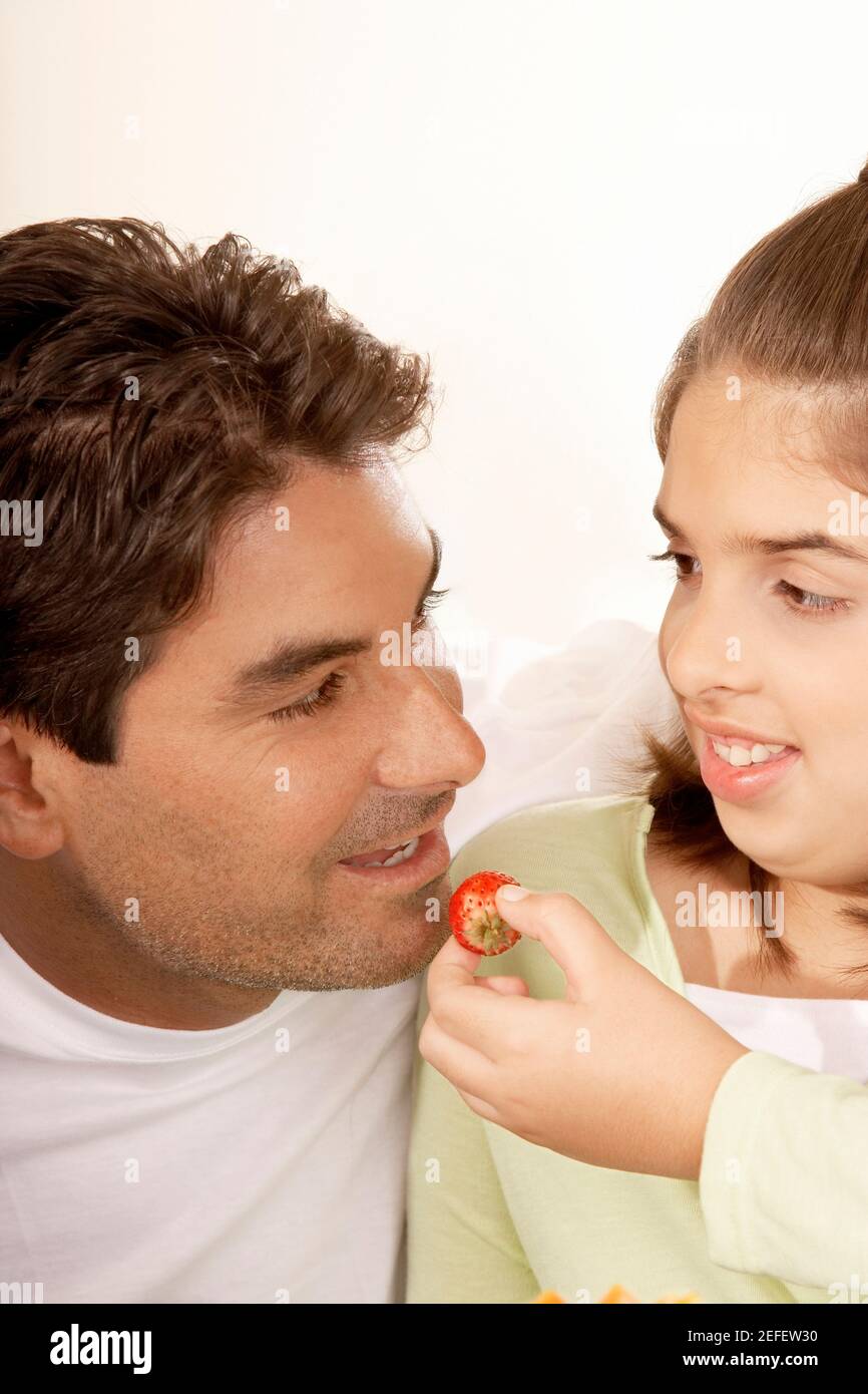 Gros plan d'une fille qui nourrit son père d'une fraise Banque D'Images