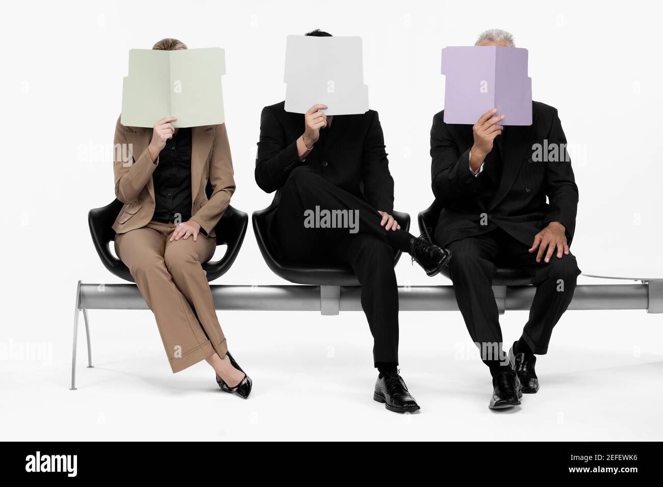 Deux hommes d'affaires et une femme d'affaires tenant des dossiers devant leurs visages Banque D'Images