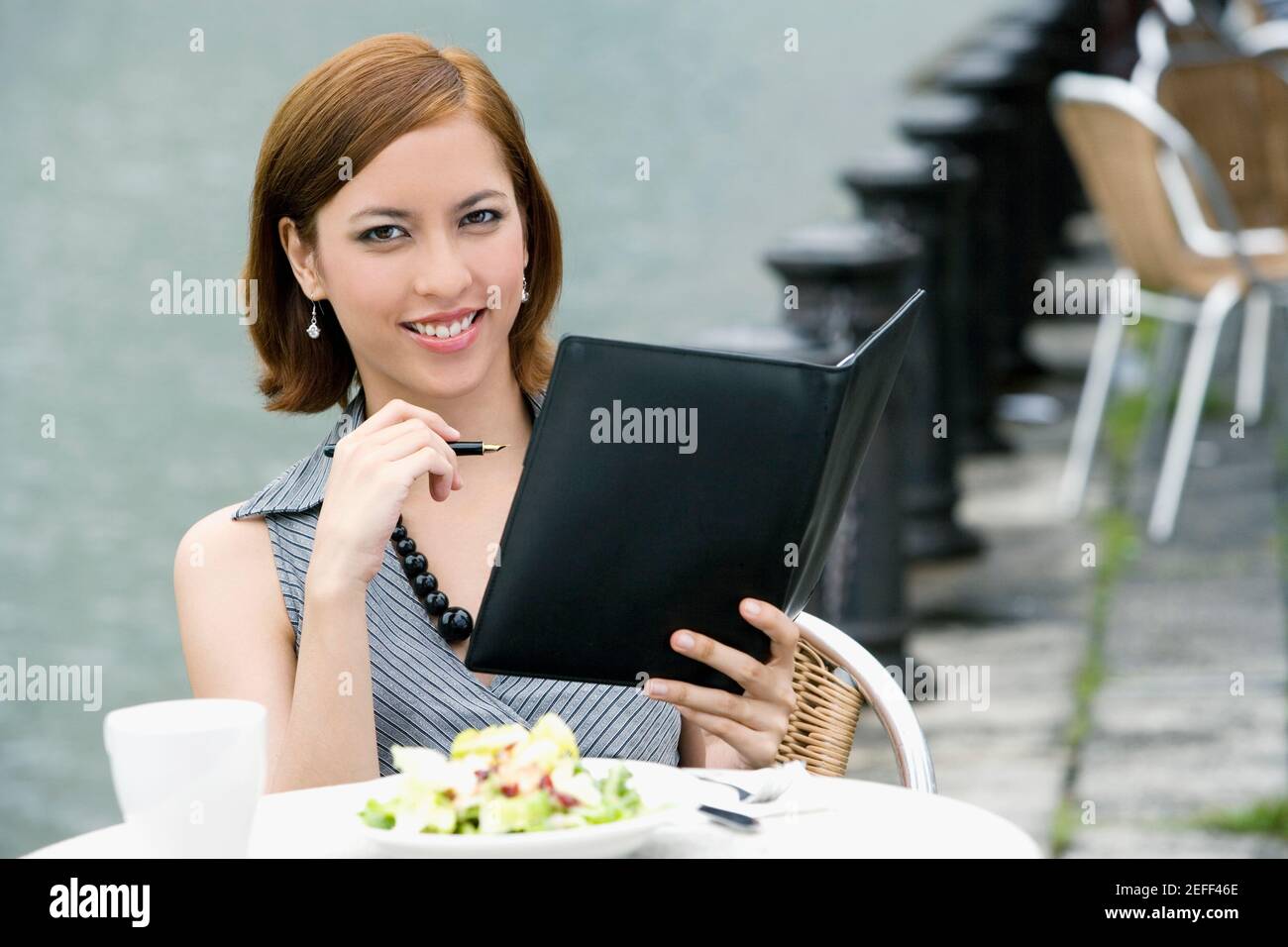 Portrait d'une femme d'affaires tenant un anneau de reliure à un café-terrasse Banque D'Images