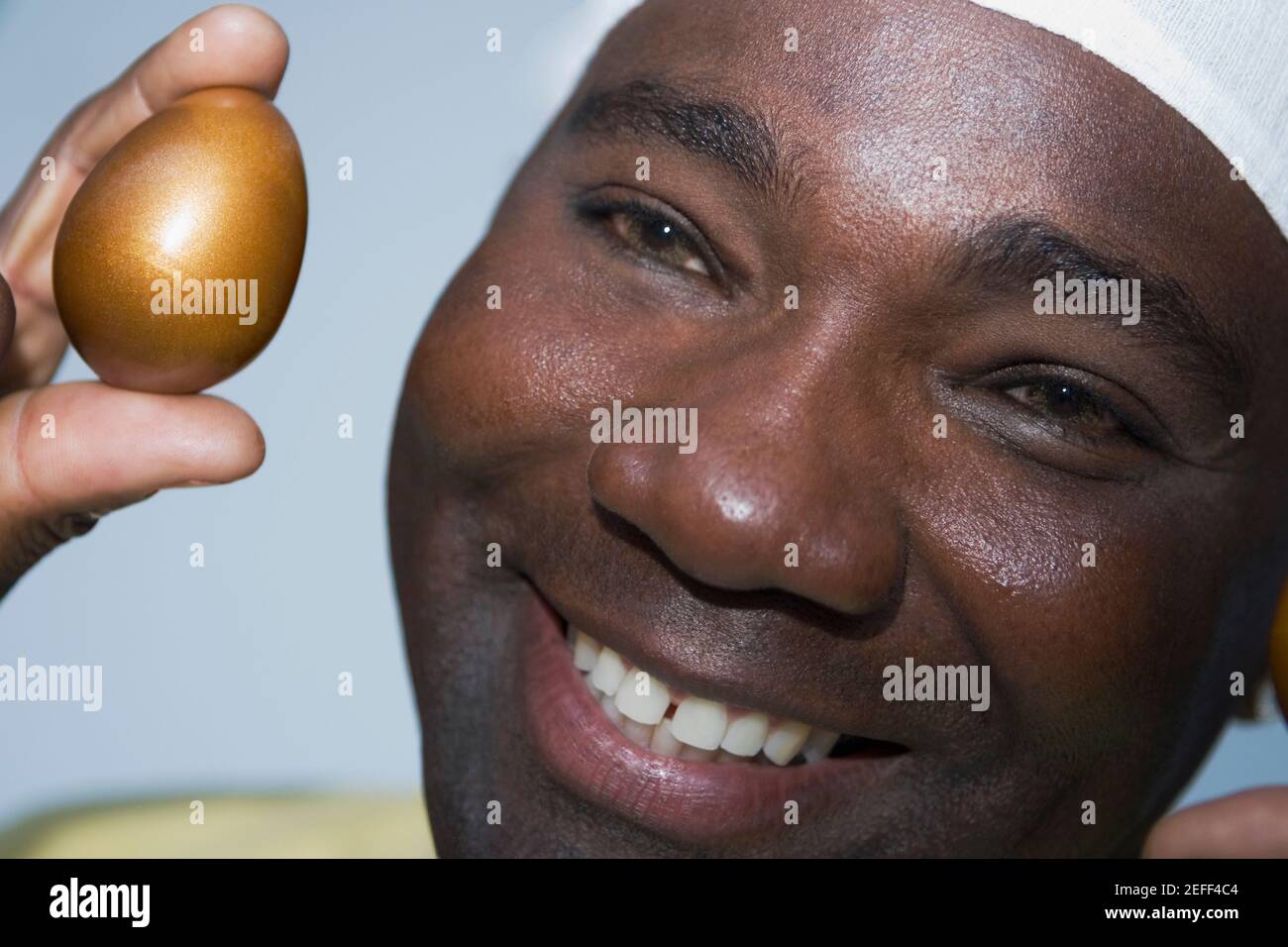 Gros plan d'un homme mature tenant un œuf doré Banque D'Images
