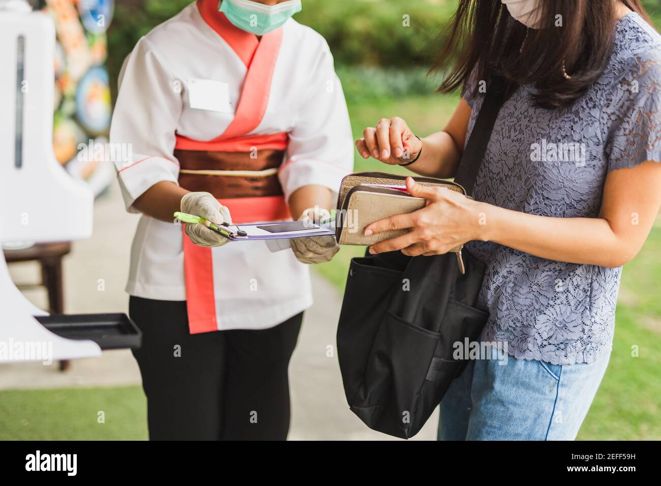 Femme serveuse dans le masque médical recevant la carte de crédit du client. Banque D'Images