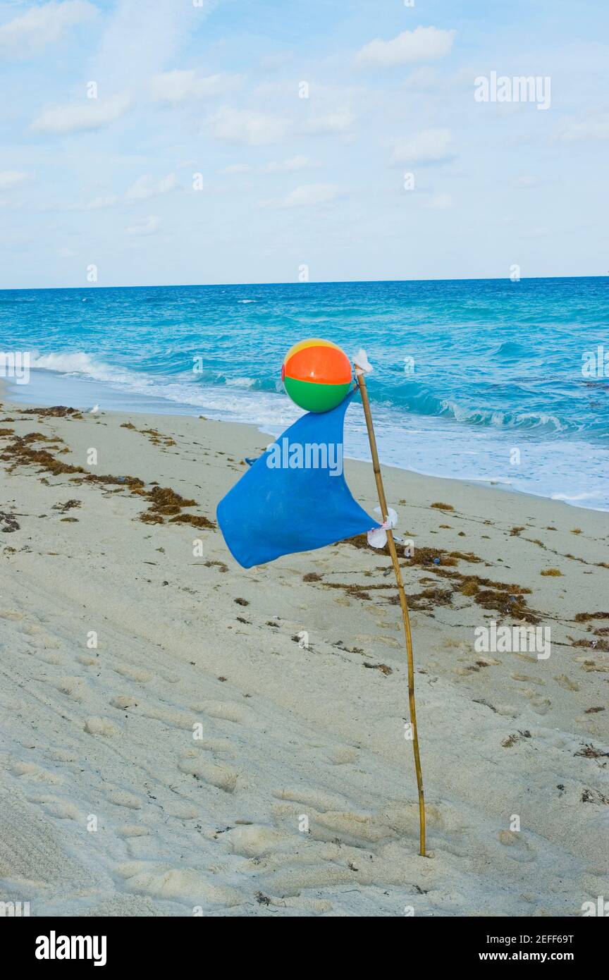 Gros plan d'un ballon de plage et d'un drapeau sur le plage Banque D'Images