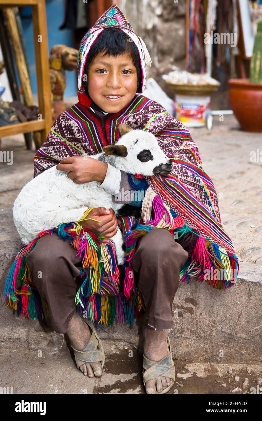 Portrait d'un garçon tenant un agneau et souriant, Pisaq, Vallée d'Urubamba, Pérou Banque D'Images