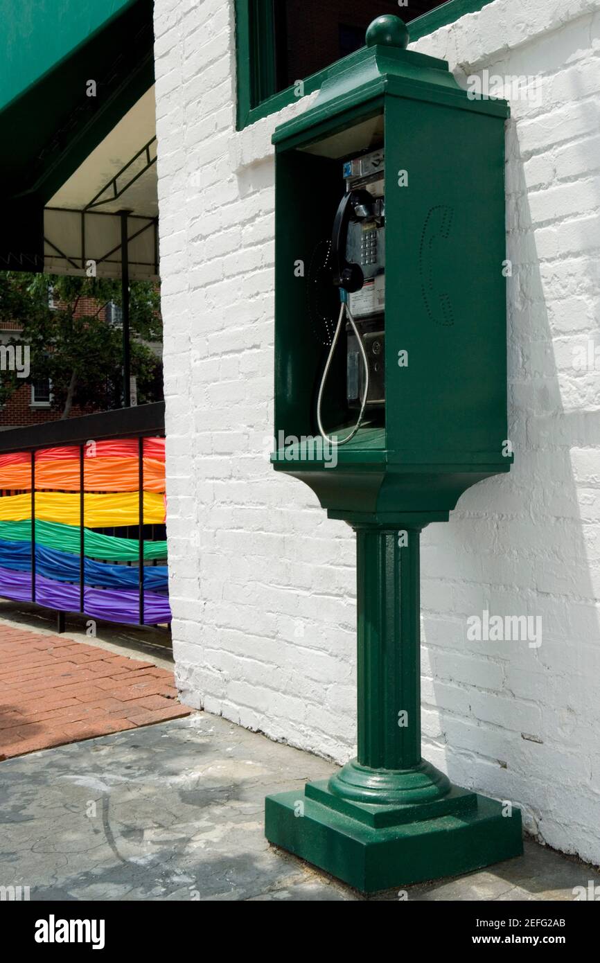 Téléphone payant près d'un bâtiment avec le drapeau arc-en-ciel l'arrière-plan Banque D'Images