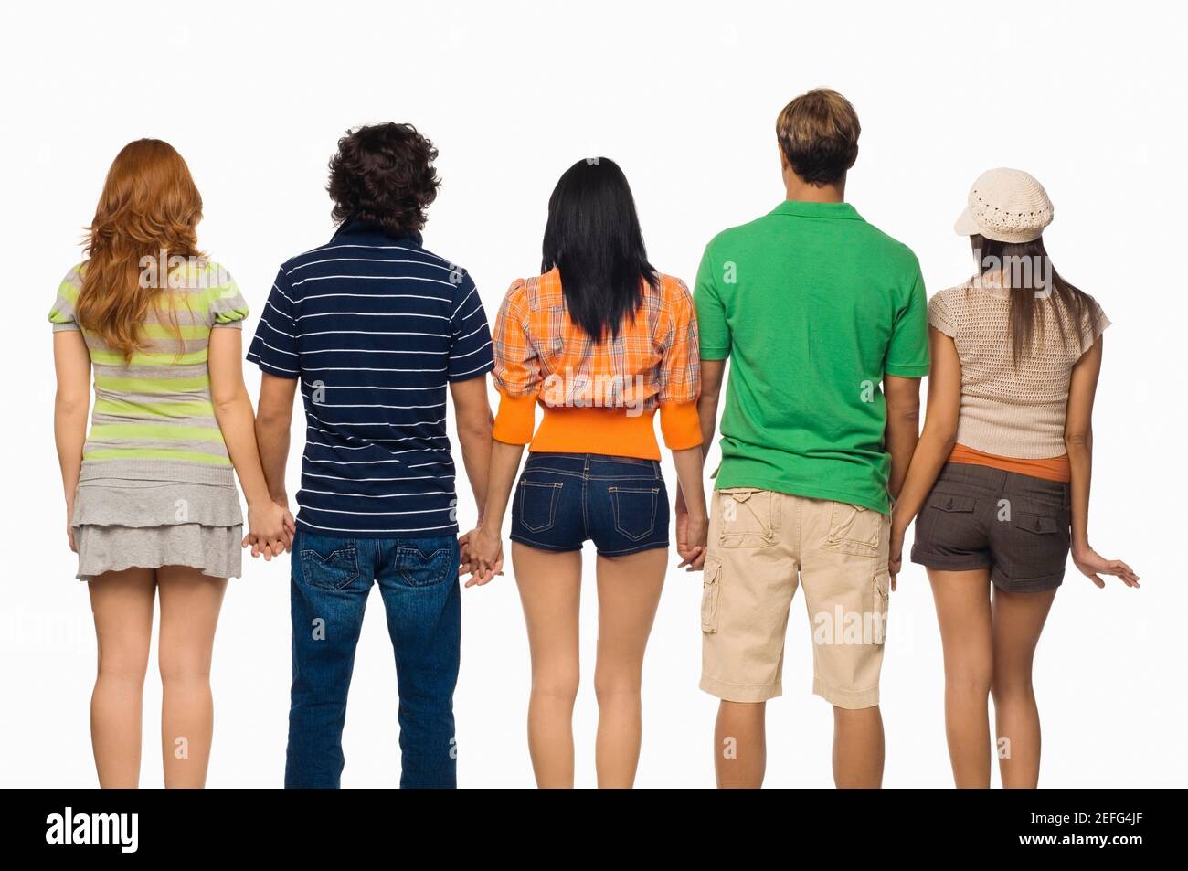 Vue arrière de trois jeunes femmes et deux hommes se tenant la main avec Banque D'Images