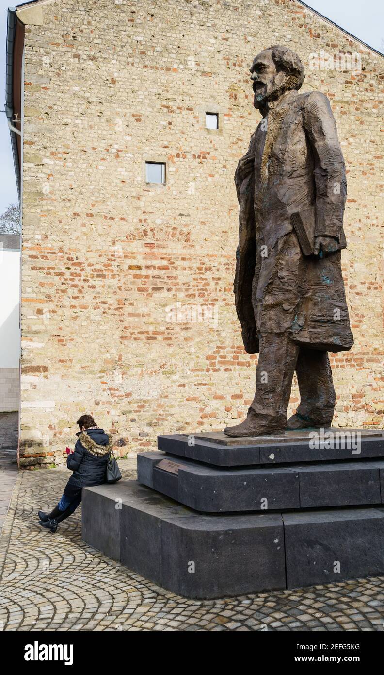 16 février 2021, Rhénanie-Palatinat, Trèves : une femme est assise sur le piédestal de la statue de Karl Marx sur Simeonstiftplatz. La statue a été dévoilée le 5 mai 2018 pour marquer le 200e anniversaire de la naissance de Karl Marx dans sa ville natale. Le philosophe, économiste, journaliste et auteur de 'Capital', critique de la société capitaliste du XIXe siècle, est né à Trèves le 5 mai 1818. Photo: Andreas Arnold/dpa Banque D'Images