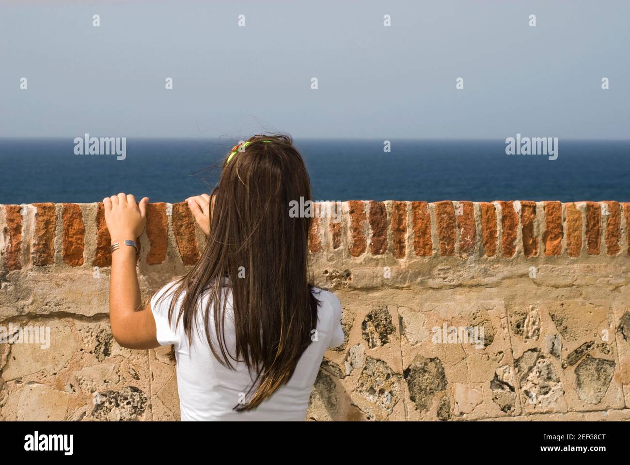Vue arrière d'une jeune femme à la recherche sur un mur de château, Château del Morro, Old San Juan, San Juan, Puerto Rico Banque D'Images